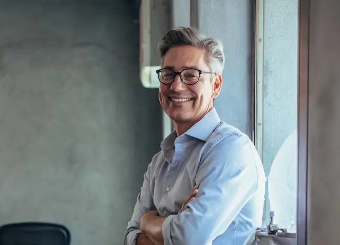 Selvsikker forretningsmann som smiler på kontoret, og representerer lederskap, positivitet